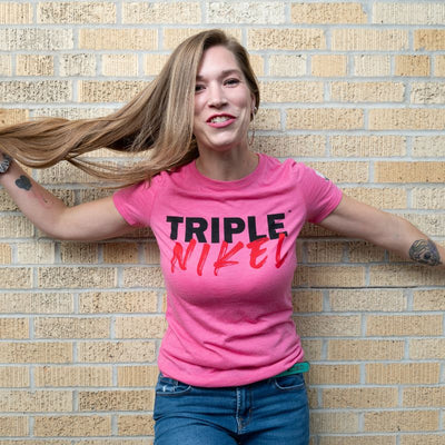 woman standing against the wall pulling her hair with a pink shirt on